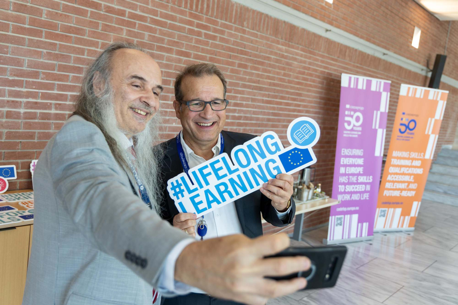 Two men holding a sign and taking a selfie