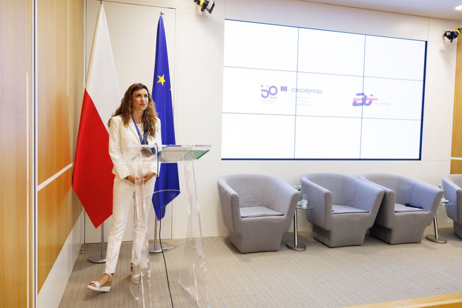 A woman speaking next to flags