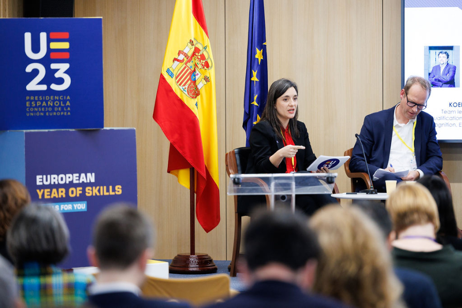 A woman and a man in a panel, flags, audience