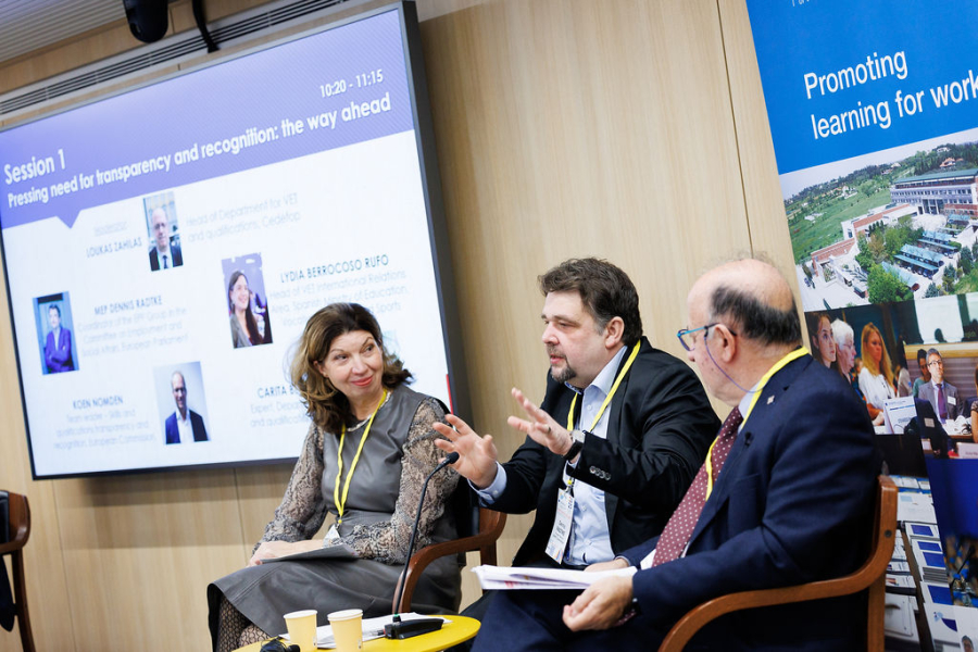 A woman and two men in a panel, banner, presentation screen